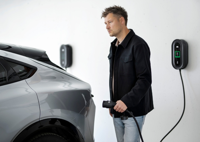 Man ready to plug in charging cable into the car, DEFA Power ev charger ready to charge