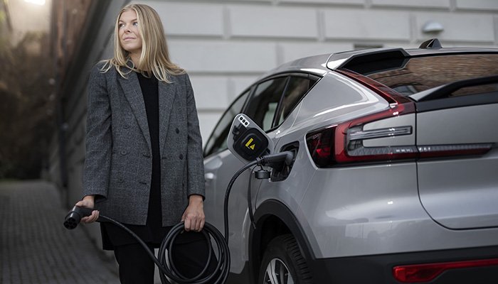 Woman holding a black eConnect Type2 charging cable connected to her car