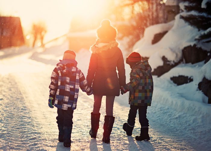 Des enfants se tenant par la main lors d'un coucher de soleil hivernal.